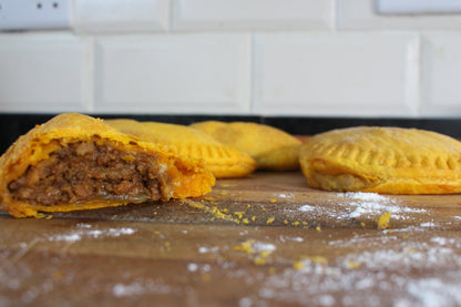 Three beef patties on a wooden board with a tiled wall in the background