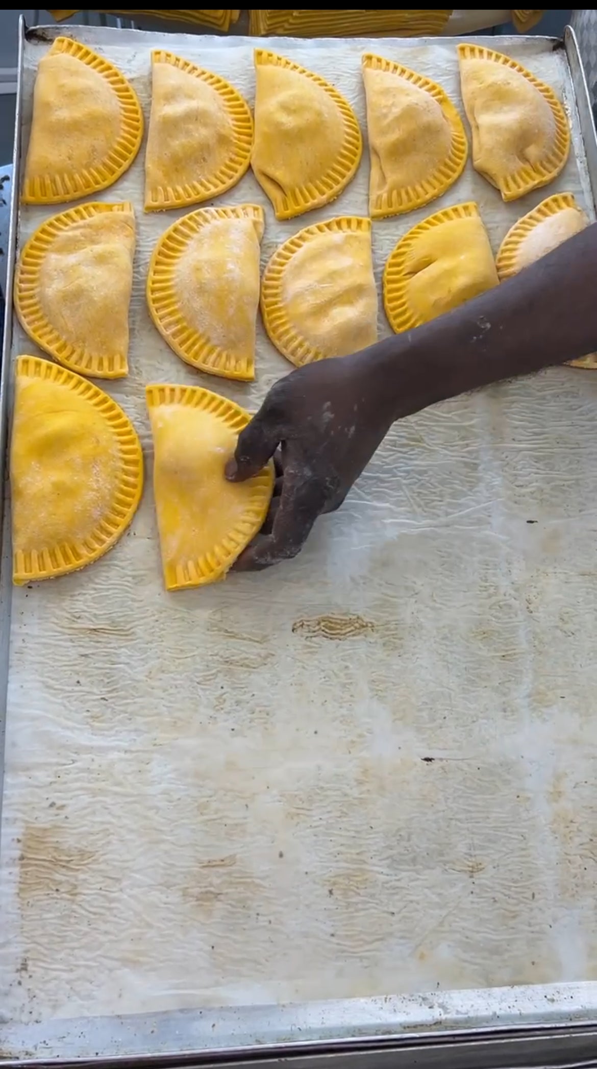 Hand arranging uncooked jamaican patty
