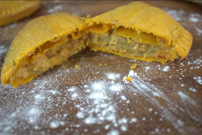 Split open Jamaican patty  on a wooden surface with flour